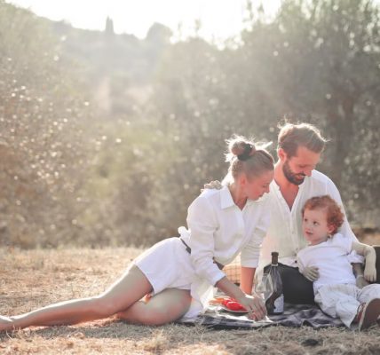 Happy family enjoying a picnic in an olive grove under the sun. Perfect for lifestyle and outdoor themes.