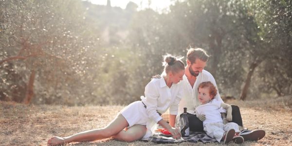 Happy family enjoying a picnic in an olive grove under the sun. Perfect for lifestyle and outdoor themes.